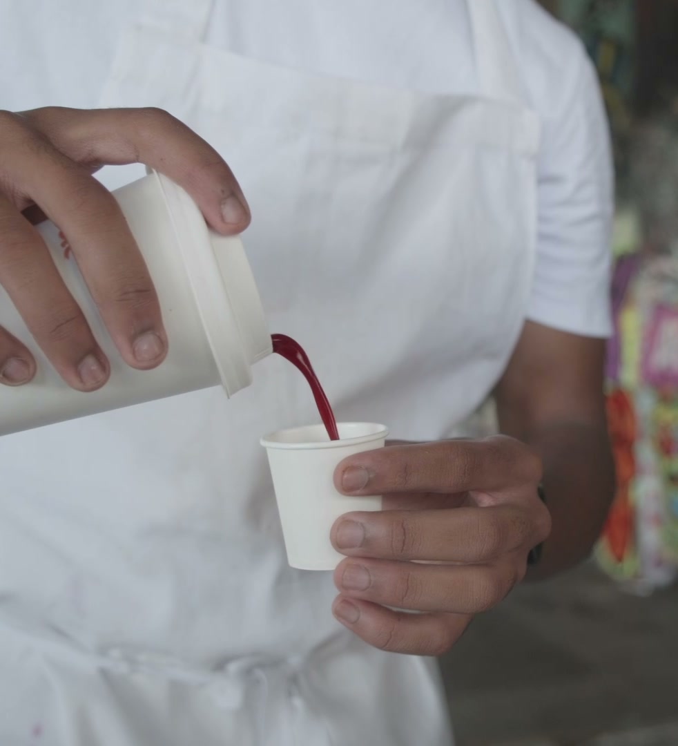 Pouring a deep red fruit blend into a cup at the stall